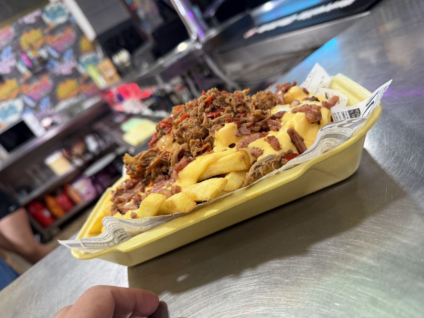 Patatas fritas cubiertas de pulled pork, queso cheddar y dados de bacon crujiente.